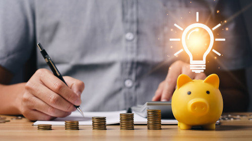 money and energy saving concept. businessman calculates savings on a table with a notebook and a piggy bank with light bulb icon. family provident fund family provident fund