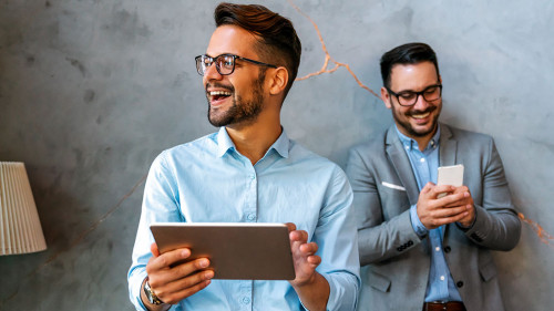 Young smiling successful business man, entrepreneur in formal business suite working on tablet
