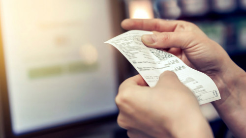 the girl looks at the receipt in the store