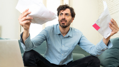 angry man paying bills as home with laptop and calculator