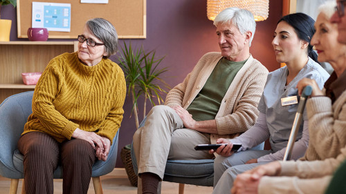 Elderly people watching TV in retirement home together