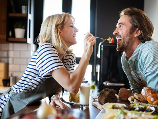 Beautiful young couple is smiling while cooking together in kitchen at home