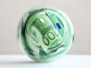 Euro banknotes in a glass jar on a grey background