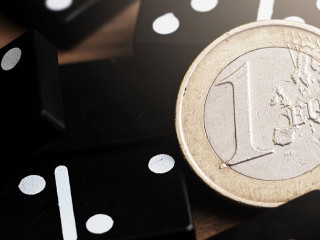 Shiny one euro coin lying on top of spilled domino tiles.