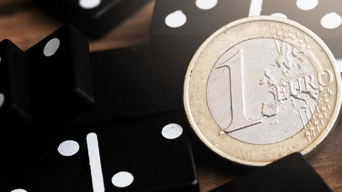 Shiny one euro coin lying on top of spilled domino tiles.