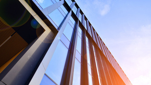 Glass modern building with blue sky background. Low angle view a