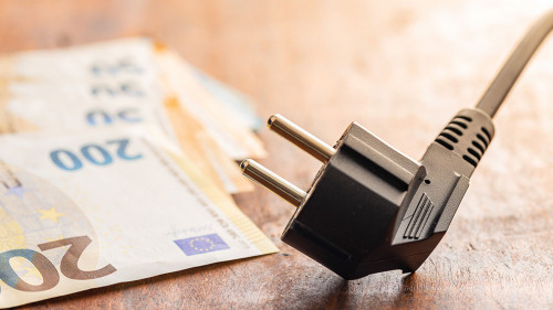Electric plug and euro money on wooden table. Concept of increasing electric prices.
