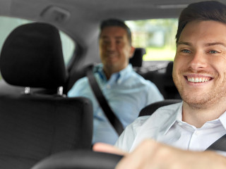 male taxi driver driving car with passenger