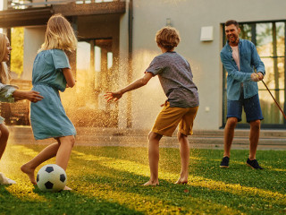 Happy Family of Four Playing with Garden Water Hose, Spraying Ea