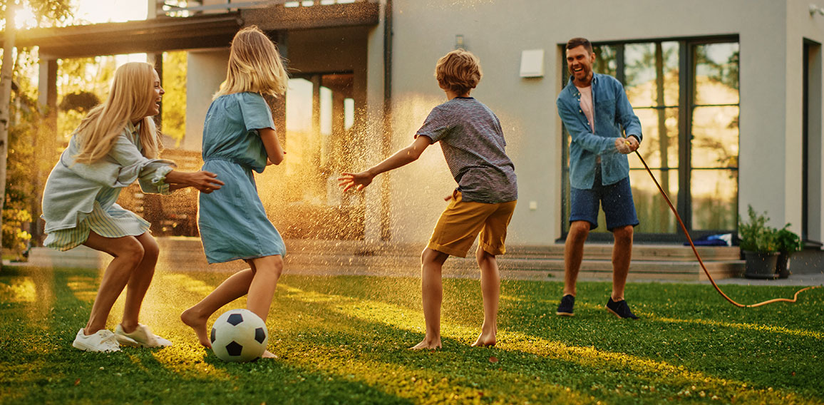 Happy Family of Four Playing with Garden Water Hose, Spraying Ea