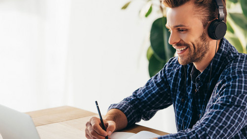 smiling man in headphones taking part in webinar at tabletop wit