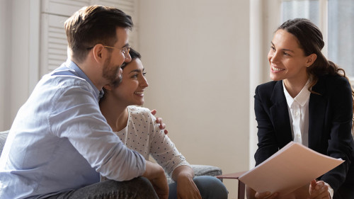 Client and banker seated on sofa discuss mortgage contract terms