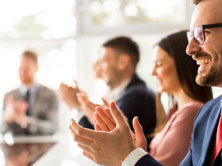 Smiling business group clapping hands at the meeting