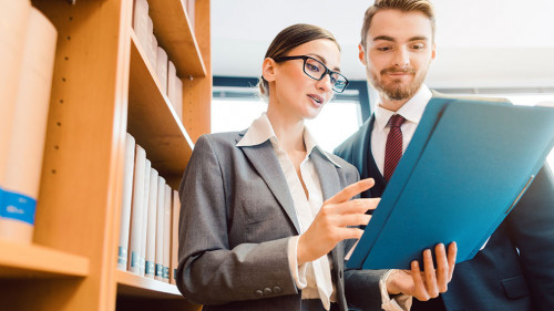 Lawyers in library of law firm discussing strategy in a case holding file