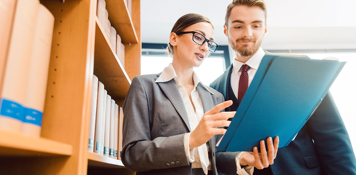 Lawyers in library of law firm discussing strategy in a case holding file
