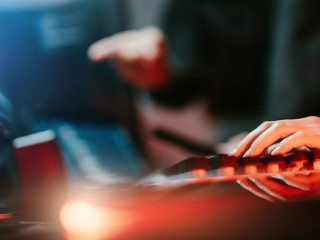 Hacker in dark room using keyboard stealing data on internet.