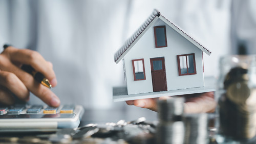 Saving investment home with loan finance money business concept. Investment banking finance for residential real estate business. Stack coins with model house for investment loans.Cash for taxes.