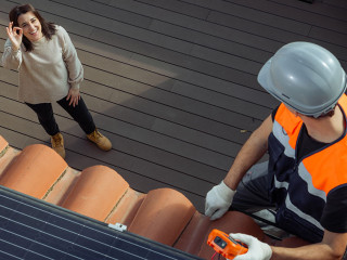 Happy customer owner of the house while worker installs solar panels