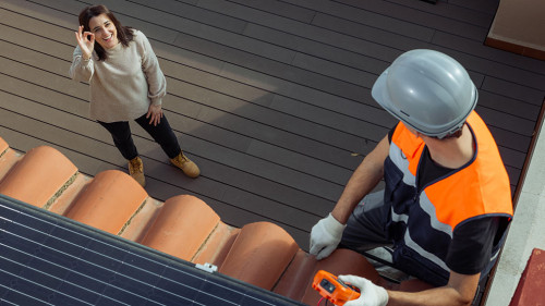 Happy customer owner of the house while worker installs solar panels