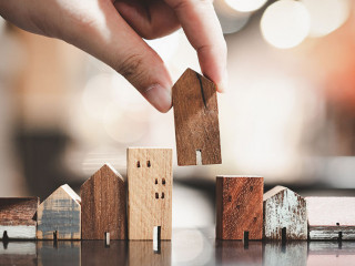 Hand choosing mini wood house model from model on wood table, se