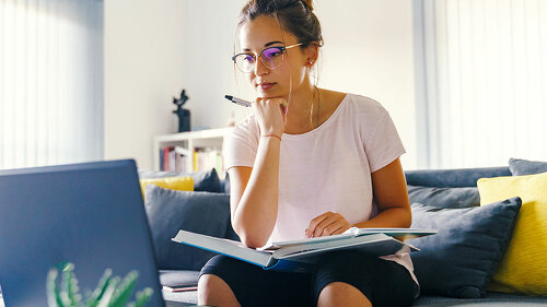Front view on young caucasian woman study in front of the laptop
