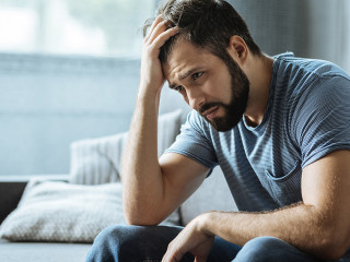 Sad gloomy man holding his forehead