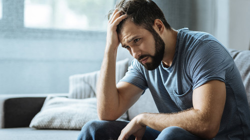 Sad gloomy man holding his forehead