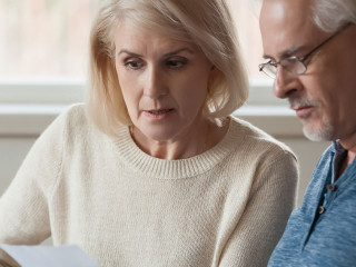 Aged couple read bank statement analyzing family expenses feels concerned