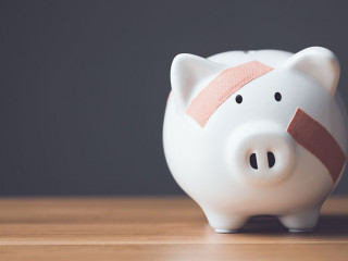 Financial problem, Bankrupt or fail in business concept. White piggy bank with plastic adhesive bandages on wooden desk with dark copy space wall background. Fail, Bankrupt or unsuccessful idea.