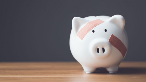 Financial problem, Bankrupt or fail in business concept. White piggy bank with plastic adhesive bandages on wooden desk with dark copy space wall background. Fail, Bankrupt or unsuccessful idea.