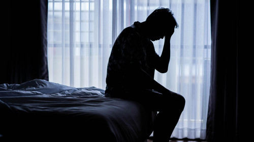 Lonely man silhouette sitting on the bed feeling depressed and s