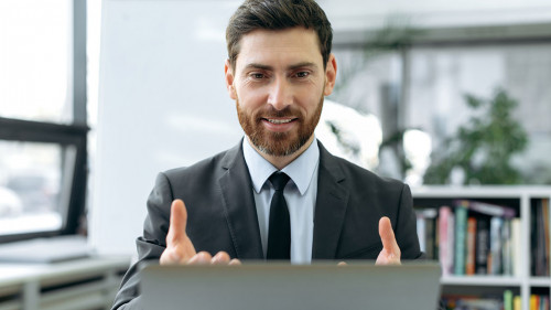 Concentrated caucasian businessman, information security engineer, insurance manager, sit in modern office, having video meeting with colleague using laptop, explaining working strategy,gestures hands