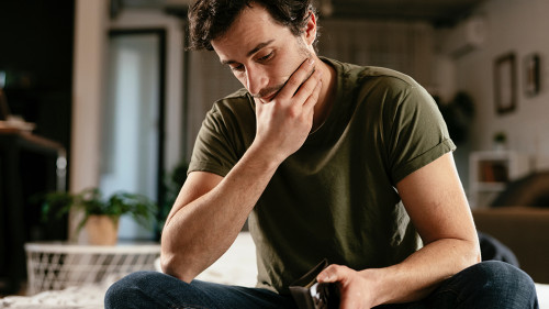 Young man checking empty wallet, no money. Unemployed sad man si