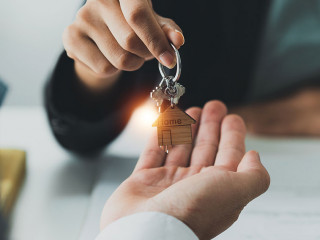 Close up Business woman or Real Estate agent giving house key after signing agreement for buying house. Bank manager and real estate concept.