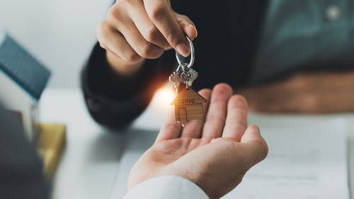 Close up Business woman or Real Estate agent giving house key after signing agreement for buying house. Bank manager and real estate concept.