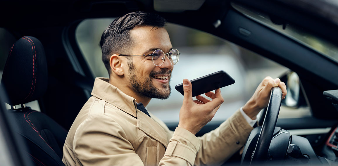 A happy businessman is driving his car and leaving voice massage