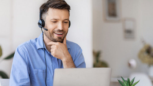 Business Education. Handsome businessman in headset watching webinar on laptop in office