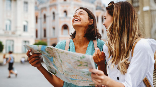 Fun, friends, travel and tourism concept. Beautiful girls looking for direction in the city