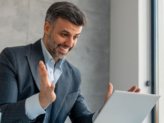 Happy confident businessman video calling on laptop, working in