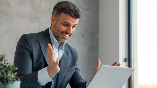 Happy confident businessman video calling on laptop, working in