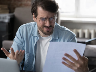 Annoyed frustrated entrepreneur looking at paper report with bad news