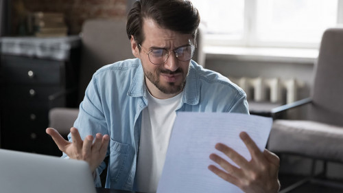 Annoyed frustrated entrepreneur looking at paper report with bad news
