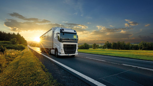White truck driving on the asphalt road in rural landscape in th