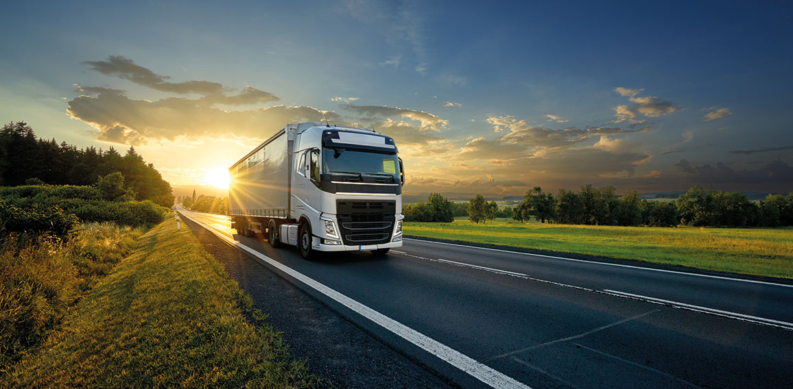 White truck driving on the asphalt road in rural landscape in th