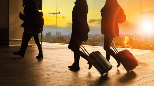 people and traveling luggage walking in airport terminal building with sun set sky at urban scene and air plane flying background