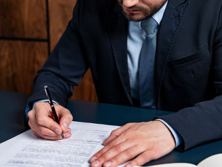 A good looking man signing the mortgage contract at the real property agent office. The concept of entering into legal power to take liabilities. Real eastate.