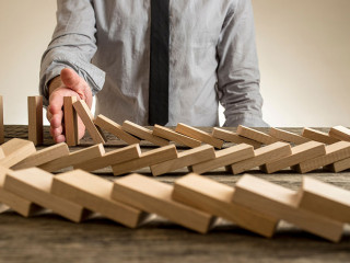 Hand stopping domino effect of wooden blocks