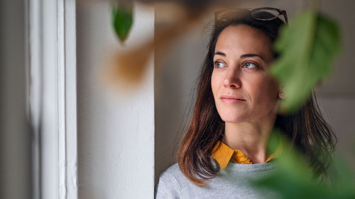 Attractive businesswoman with coffee standing indoors in office, resting.