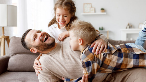 Kids playing with father on sofa