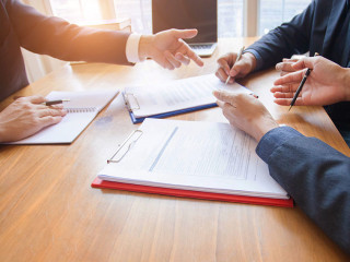 business people and lawyers discussing contract papers sitting a